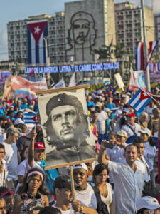 Cubans file past, one holding a poster that depicts revolutionary hero Ernesto "Che" Guevara, in the annual May Day parade at Revolution Square in Havana, Cuba, Tuesday, May 1, 2018. (AP Photo/Desmond Boylan)