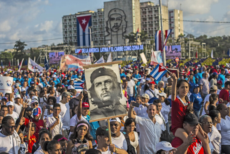 Cubans file past, one holding a poster that depicts revolutionary hero Ernesto "Che" Guevara, in the annual May Day parade at Revolution Square in Havana, Cuba, Tuesday, May 1, 2018. (AP Photo/Desmond Boylan)